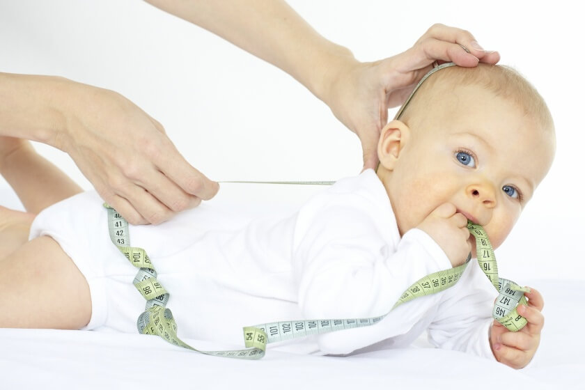 Körpergröße beim Baby messen Frau misst Körpergröße ihres Babys