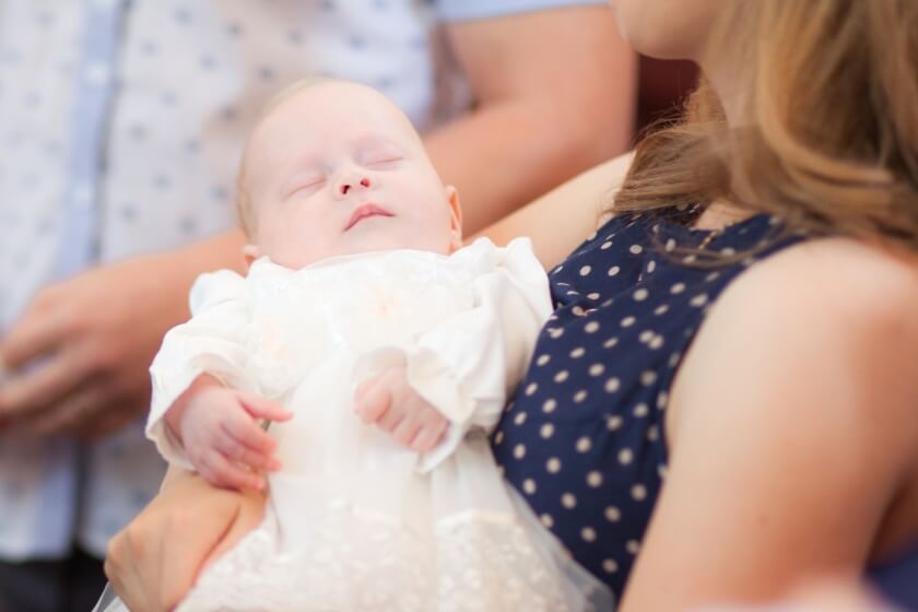 Patentante trägt Baby bei der Taufe