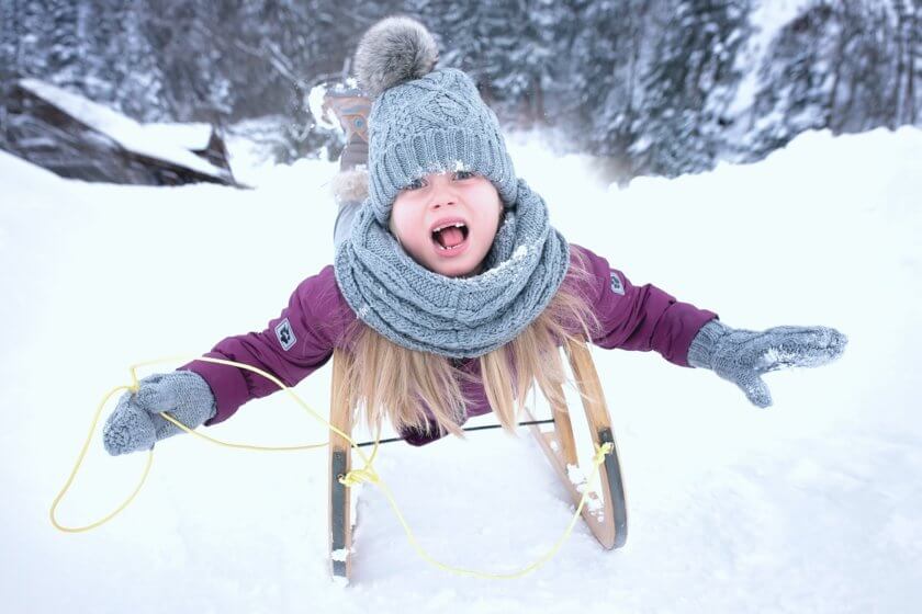 Mädchen fährt mit Holzschlitten Schneeberg hinunter