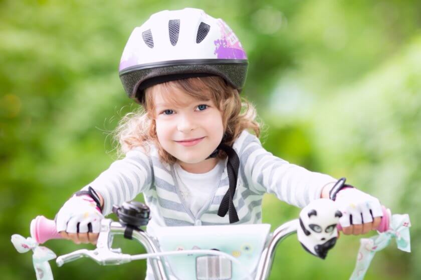 Kind fährt mit sicherem Kinderfahrradhelm auf dem Fahrrad