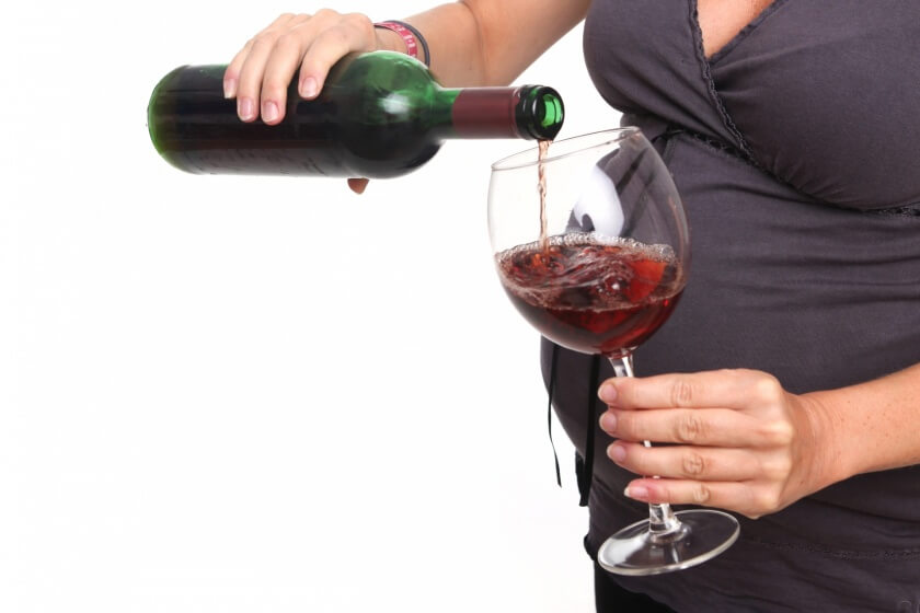 Schwangere Frau schenkt sich Wein ein