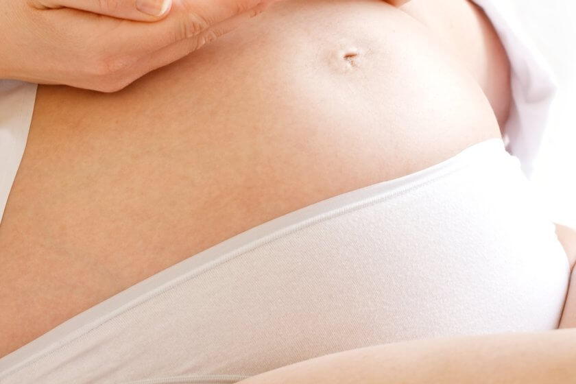 Schwangere mit Babybauch und Stützgürtel