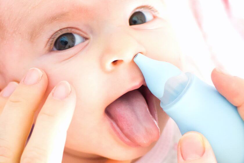 Mutter saugt verstopfte Babynase mit Nasensauger ab