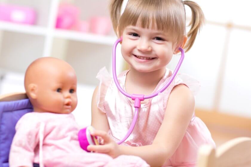 Mädchen spielt mit ihrer Puppe Arzt