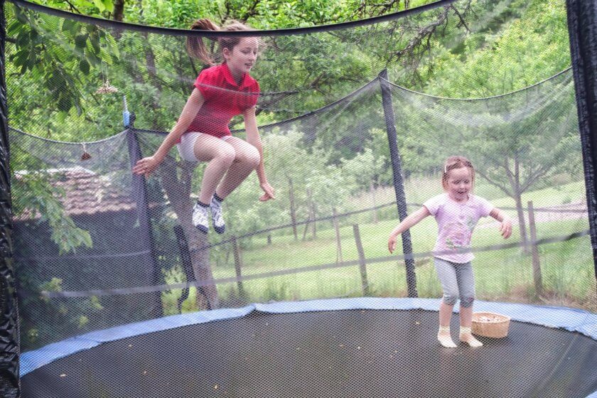 Kinder springen auf Gartentrampolin mit Netz