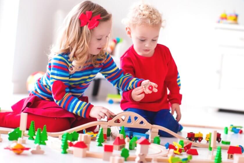 Kleinkinder spielen mit Holzeisenbahn im Kinderzimmer